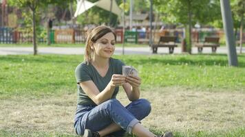 Happy woman counting money in the park. video