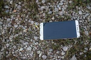 teléfono con roto pantalla. el caído en el piedras teléfono inteligente con agrietado vaso. foto