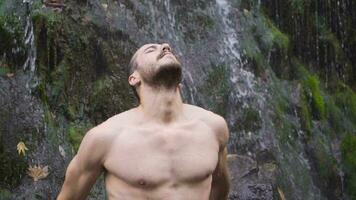 muskulös Mann und Wasserfall. schleppend Bewegung. video