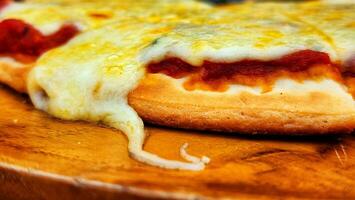 Pizza con queso, tomate y queso Mozzarella en un de madera tablero foto