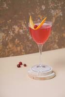 Pink alcoholic cocktail in steamed glass on wooden podium or pedestal photo