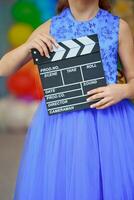 Clapperboard in the hands of a girl in a blue evening dress. photo