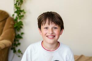 retrato de sonriente adolescente chico mirando a cámara a hogar. niño riendo foto