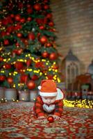 pequeño sorprendido niño en Papa Noel disfraz en festivo habitación en Navidad víspera. niña en antecedentes de Navidad árbol. foto