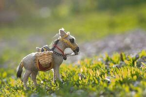 A donkey in a clearing of green grass. A loaded donkey on a green background. photo