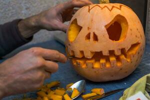 family fun activity. arved pumpkins into jack-o-lanterns for halloween. Carving big orange pumpkins for Halloween in late Autumn. photo