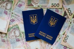 Two international passport of Ukrainians lie on pile of money from five hundred-pound banknotes. Passports for departure to Europe without visas. Visa-free regime for Ukraine. photo