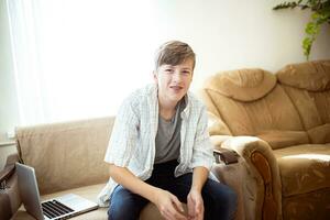 A teenager with braces on his teeth sits in the living room. The smiling guy in the room. photo