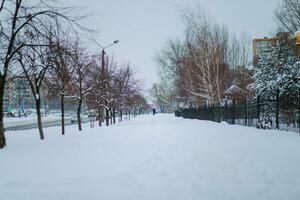 Unpolished pavements after winter snowfall. The road is covered with deep snow. Paths trodden in the snow. photo