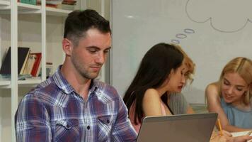 Cheerful young man smiling joyfully while working on his laptop video