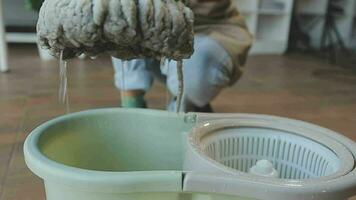 huisvrouw gebruik makend van vacuüm schoonmaakster Aan de vloer. vervelend een schort naar schoon de leven kamer Bij huis. jong vrouw is gelukkig naar schoon huis. hulp in de huishouding schoonmaak onderhoud. video