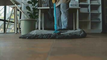 huisvrouw gebruik makend van vacuüm schoonmaakster Aan de vloer. vervelend een schort naar schoon de leven kamer Bij huis. jong vrouw is gelukkig naar schoon huis. hulp in de huishouding schoonmaak onderhoud. video