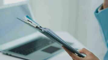 Beautiful Asian woman sitting in the office using a laptop. Happy business woman smiling and enjoying her work and taking note on a notepad. video