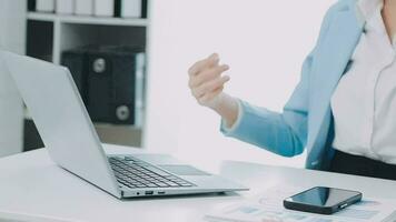 Beautiful Asian woman sitting in the office using a laptop. Happy business woman smiling and enjoying her work and taking note on a notepad. video