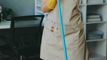 hemmafru använder sig av Vakuum rengöringsmedel på de golv. bär ett förkläde till rena de levande rum på hus. ung kvinna är Lycklig till rena Hem. hembiträde rengöring service. video