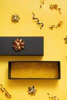 Black friday sale concept. Black gift box with copy space and festive decorations on yellow background flat lay, top view. photo