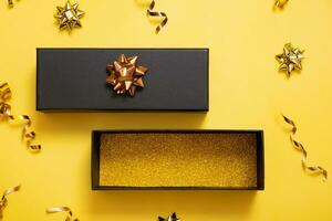 Black friday sale concept. Black gift box with copy space and festive decorations on yellow background flat lay, top view. photo