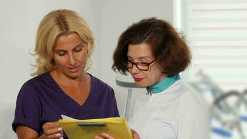 Female doctors examining medical survey documents at the clinic video