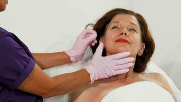 Envejecido mujer sonriente mientras cosmetóloga examinando su cara video