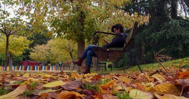 kvinna Sammanträde på en bänk på en parkera video