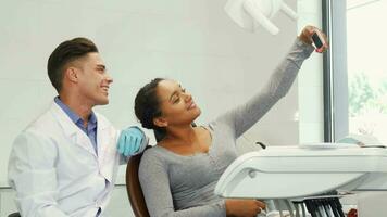 Happy woman taking a selfie with her dentist using smart phone video