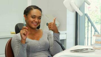 Attractive woman with perfect smile showing thumbs up and a toothbrush video