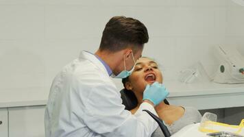Cheerful male dentist smiling while examining teeth of a female patient video
