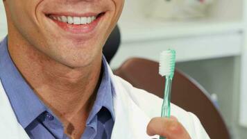 masculino dentista sorridente com perfeito dentes segurando uma escova de dente video
