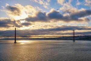 View of 25 de Abril Bridge over Tagus river on sunset. Lisbon, Portugal photo