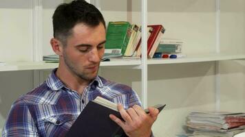 bonito jovem homem sorridente alegremente enquanto lendo uma livro video