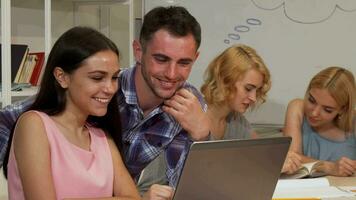 Happy students smiling to the camera while using laptop video