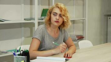 Gorgeous young woman making notes while studying video