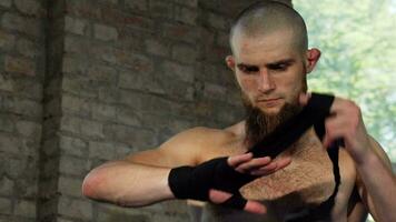 Bearded male boxer wrapping his knuckles before fighting video