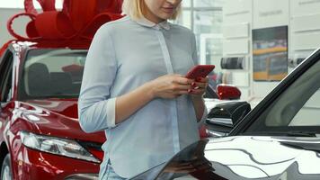 donna utilizzando sua inteligente Telefono a il auto concessionaria salone video