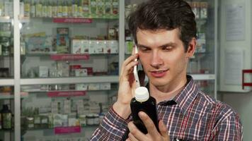 Jeune homme en utilisant intelligent téléphone tandis que achats à le pharmacie video