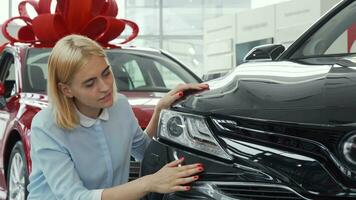 hermosa mujer sonriente a el cámara mientras examinando un nuevo automóvil video