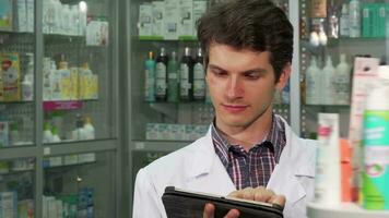 Handsome professional pharmacist doing inventory using digital tablet video