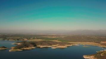 aéreo zangão vôo sobre uma lago, água barragem, com montanhas, e barcos em litoral, às nascer do sol. lindo sonhadores panorama visualizar. video