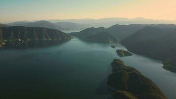 Antenne Drohne fliegend Über ein See, Wasser Damm, mit Berge beim Sonnenaufgang. wunderschön verträumt Landschaft Sicht. video
