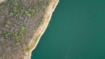 Antenne Drohne fliegend Über ein See, Wasser Damm, mit Berge, und Boote auf Küste, beim Sonnenaufgang. wunderschön verträumt Landschaft Sicht. video