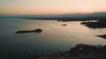 aéreo zangão vôo sobre uma lago, água barragem, com montanhas às nascer do sol. lindo sonhadores panorama visualizar. video