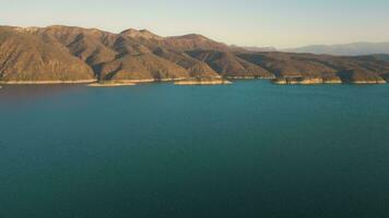 aéreo zangão vôo sobre uma lago, água barragem, com montanhas às nascer do sol. lindo sonhadores panorama visualizar. video