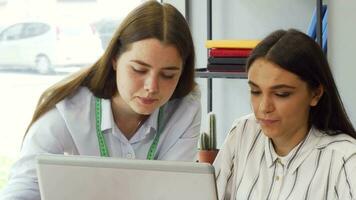 Two young businesswomen working on a computer together video