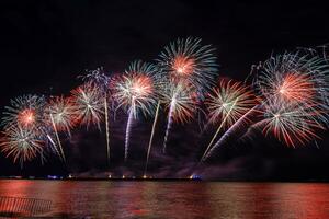 Amazing beautiful colorful fireworks display on celebration night, showing on the sea beach with multi color of reflection on water photo