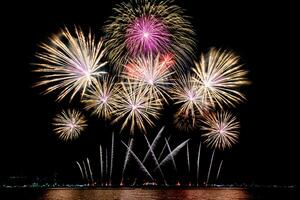 Increíble y hermoso colorido espectáculo de fuegos artificiales en la noche de celebración, que se muestra en la playa del mar con reflejos multicolores sobre el agua foto