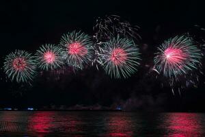 Amazing beautiful colorful fireworks display on celebration night, showing on the sea beach with multi color of reflection on water photo