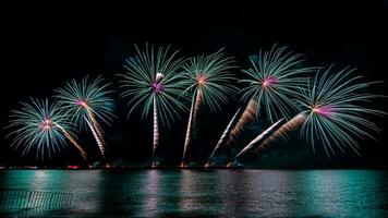 Increíble y hermoso colorido espectáculo de fuegos artificiales en la noche de celebración, que se muestra en la playa del mar con reflejos multicolores sobre el agua foto