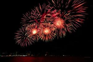 Increíble y hermoso colorido espectáculo de fuegos artificiales en la noche de celebración, que se muestra en la playa del mar con reflejos multicolores sobre el agua foto