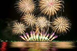 Amazing beautiful colorful fireworks display on celebration night, showing on the sea beach with multi color of reflection on water photo