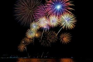Amazing beautiful colorful fireworks display on celebration night, showing on the sea beach with multi color of reflection on water photo